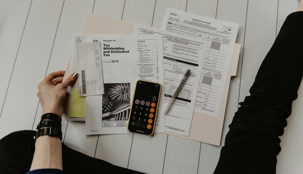 Folders of paperwork with a calculator and pen on a table