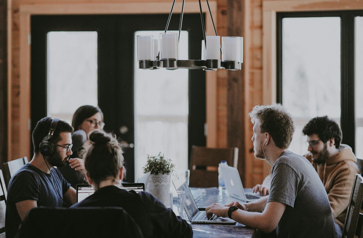 Group of people working together on laptops around a table